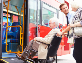 medical staff taking patient in wheelchair in a bus